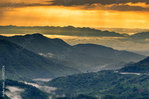 abstract background blur view of the sun shining through the clouds,surrounded by large mountains and various species of trees