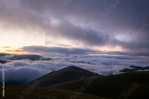 grassy mountains landscape with fog sky and sunset