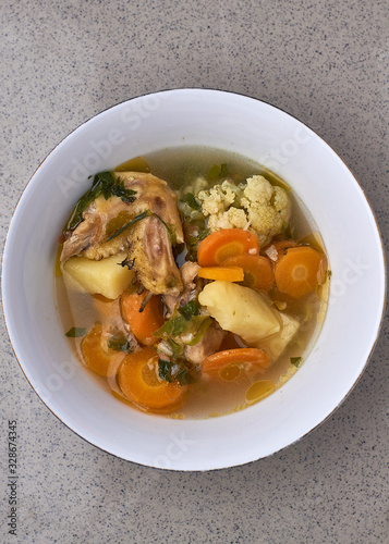 Chicken vegetable soup in white bowl, Indonesian food on a gray background