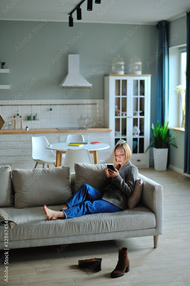 Woman use of smartphone in the evening at home while laying on sofa Woman use of smartphone in the evening at home while laying on sofa