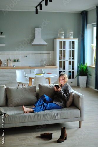 Woman use of smartphone in the evening at home while laying on sofa