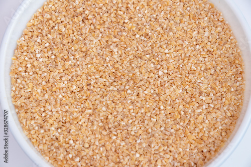Bulgur (Daliya) in bowl, Bulgur wheat grains,  Raw cereal food, Dried cracked wheat.