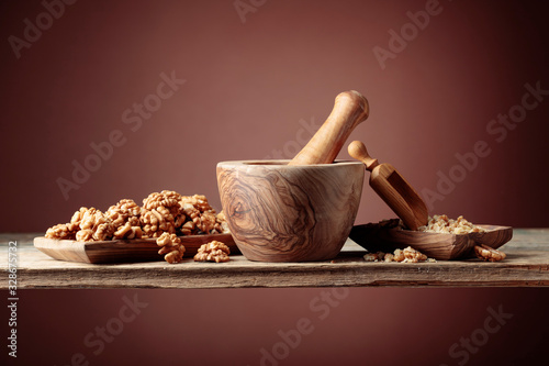 Crushed and whole walnuts in a wooden dish on an old wooden table.