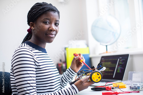 Portrait Of Female Teenage Pupil Building Robot Car In Science Lesson photo