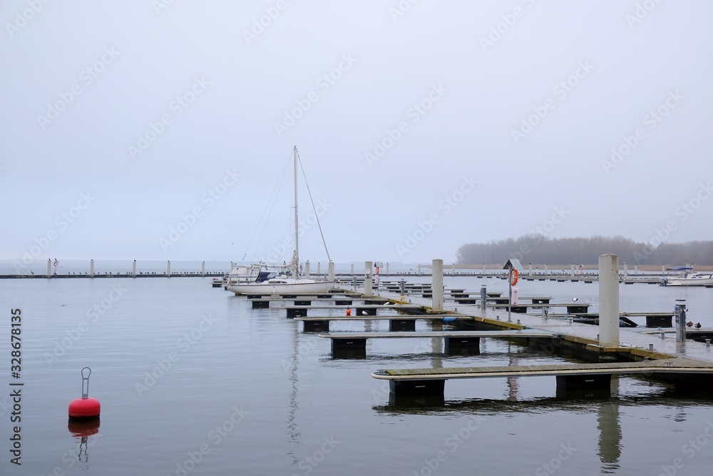 Moody landscape. Empty marina at the lake in a foggy day before the season.  Kamien Pomorski, Poland