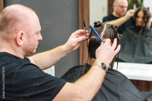 Hairdresser combs female hair.