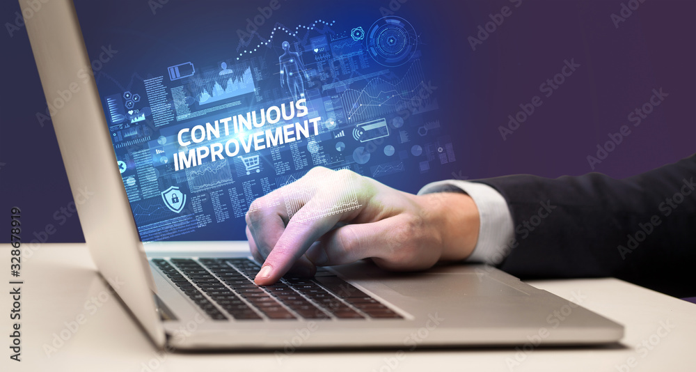 Businessman working on laptop with CONTINUOUS IMPROVEMENT inscription, cyber technology concept Businessman working on laptop with CONTINUOUS IMPROVEMENT inscription, cyber technology concept