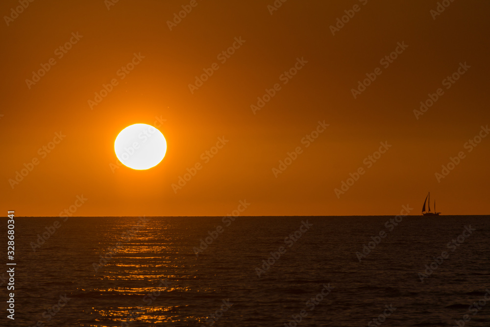 Sunset with a sailing boat on the horizon