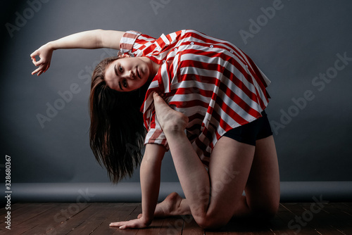 Young yoga woman practicing yoga concept, doing one-legged exercises King Pigeon, Pada Rajakapotasana pose, working out, wearing casual clothes, serious look camera, gray loft studio background photo