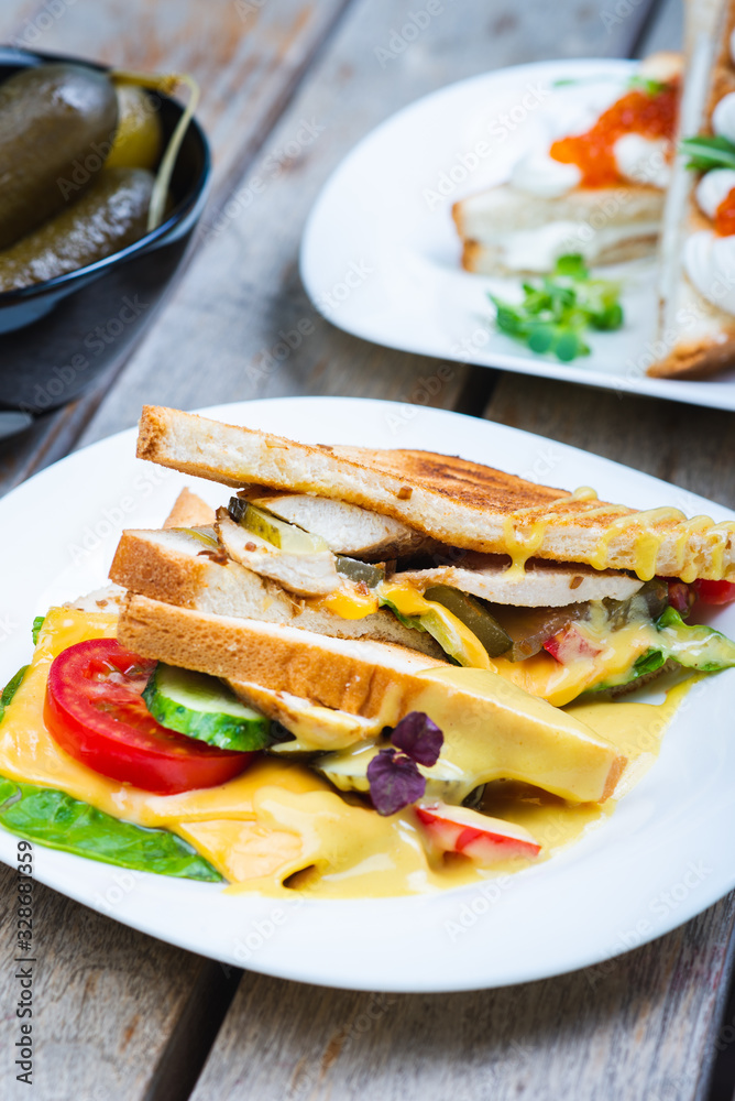 Classic breakfast, hot sandwiches with cheese, vegetables and chicken on a wooden table. Classic breakfast, hot sandwiches with cheese, vegetables and chicken on a wooden table.