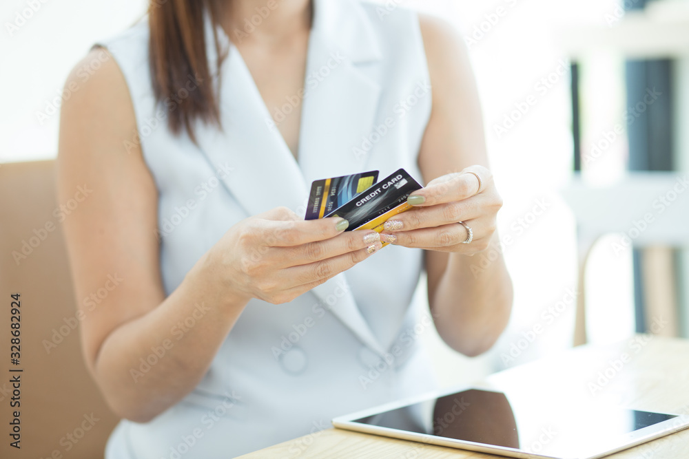 .Asian women holding a credit card and entering the security code using a laptop, online payments app smartphone in a shop, concept: Business e-Commerce banking ordering transactions for technology .Asian women holding a credit card and entering the security code using a laptop, online payments app smartphone in a shop, concept: Business e-Commerce banking ordering transactions for technology