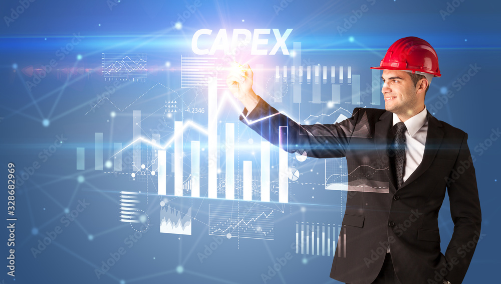 Handsome businessman with helmet drawing CAPEX inscription, architecture business plan concept Handsome businessman with helmet drawing CAPEX inscription, architecture business plan concept