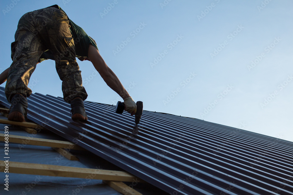 Work with a screwdriver on the roof of a residential house in the open air close up