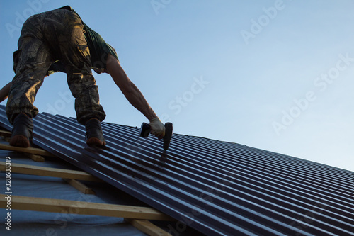 Work with a screwdriver on the roof of a residential house in the open air close up