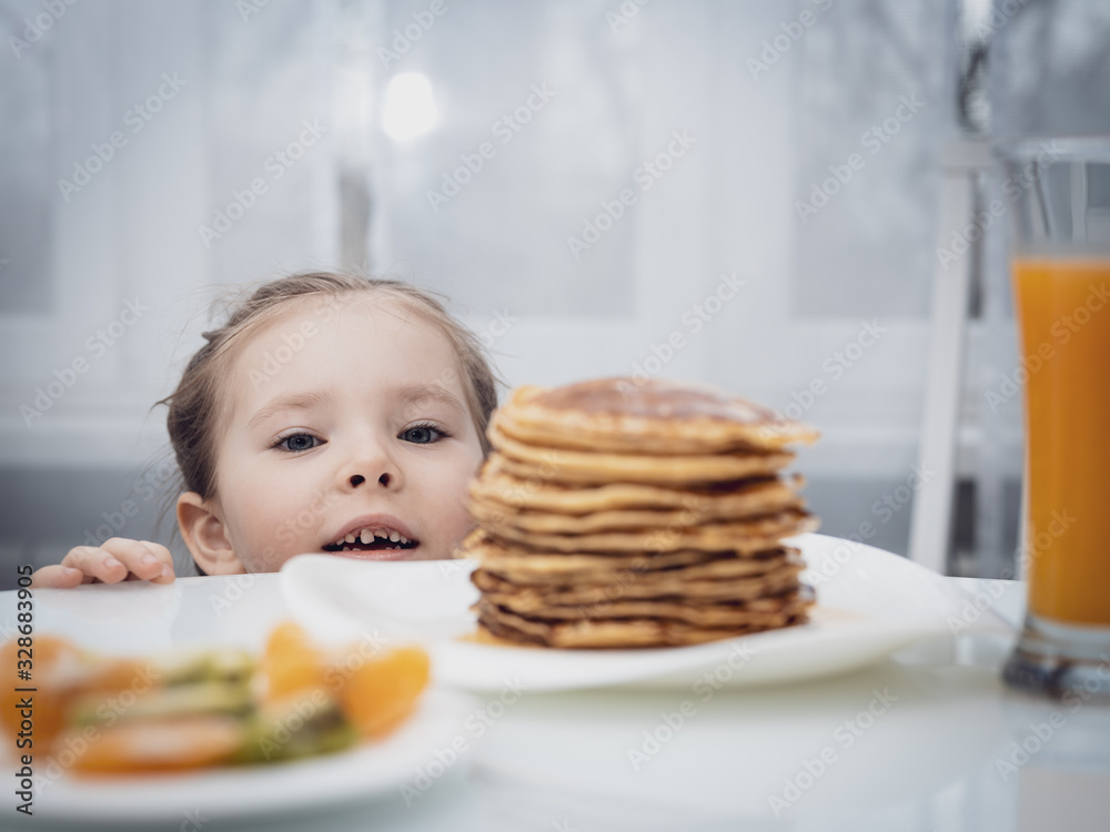Selected focus. Little kid looking at homemade pancakes with honey on table Selected focus. Little kid looking at homemade pancakes with honey on table