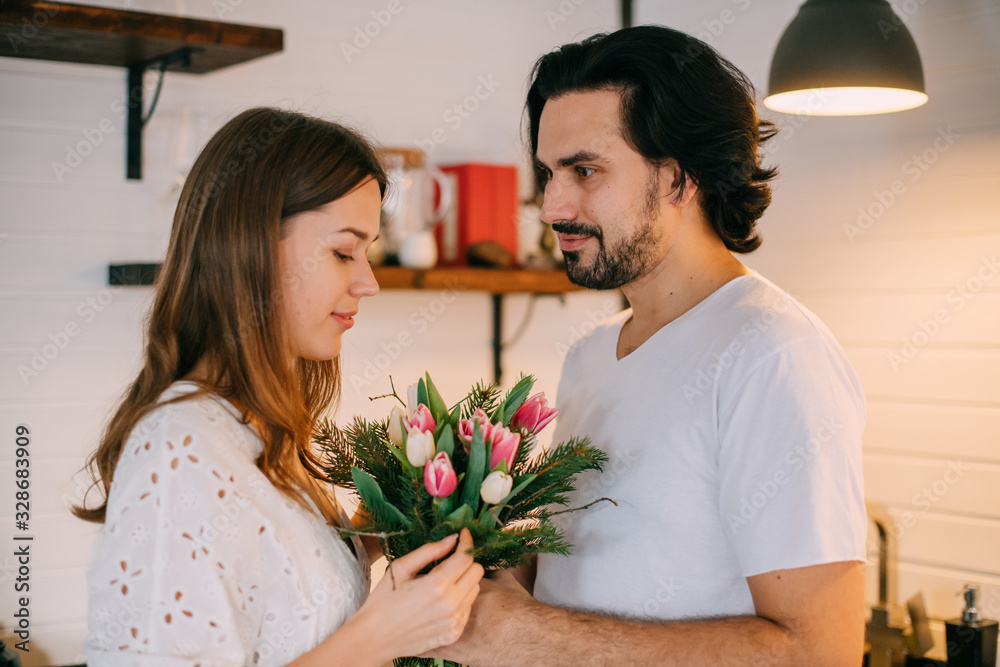 International Women's Day. Young couple in the morning in the kitchen at home International Women's Day. Young couple in the morning in the kitchen at home