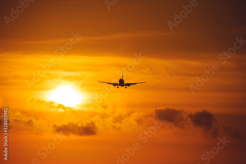 Silhouette of a passenger airliner in the sky during sunset. Airplane in the sky. © Evgenii Starkov