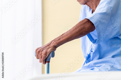 Senior man patient with walking stick in the hospital room.
