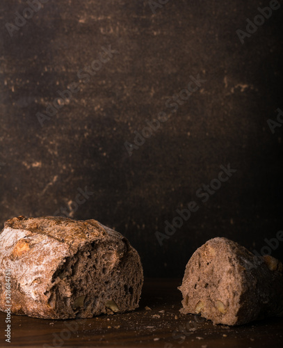 A small cut bread made with nuts on a wooden table. Dark background. Vertical format