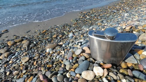 vintage metal hip flask on pebbles on a beach. celebration of men's holiday at sea. conception International Men's Day and Fatherland defender day February 23. copy space photo