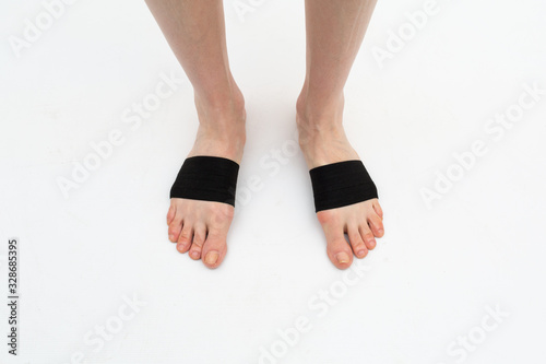 cuff-tie for the anterior part of the foot with a metatarsal roller on the legs of a woman to correct the big toe for hallux valgus, 2 legs, isolated close-up, white background
