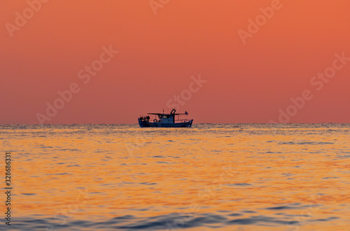 Sunset over the sea. Silhouette of fisherman boat
