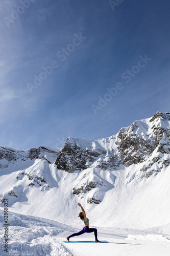 A young woman practice yoga in mountains. With a great view of snow and winter landscape. © localcinema