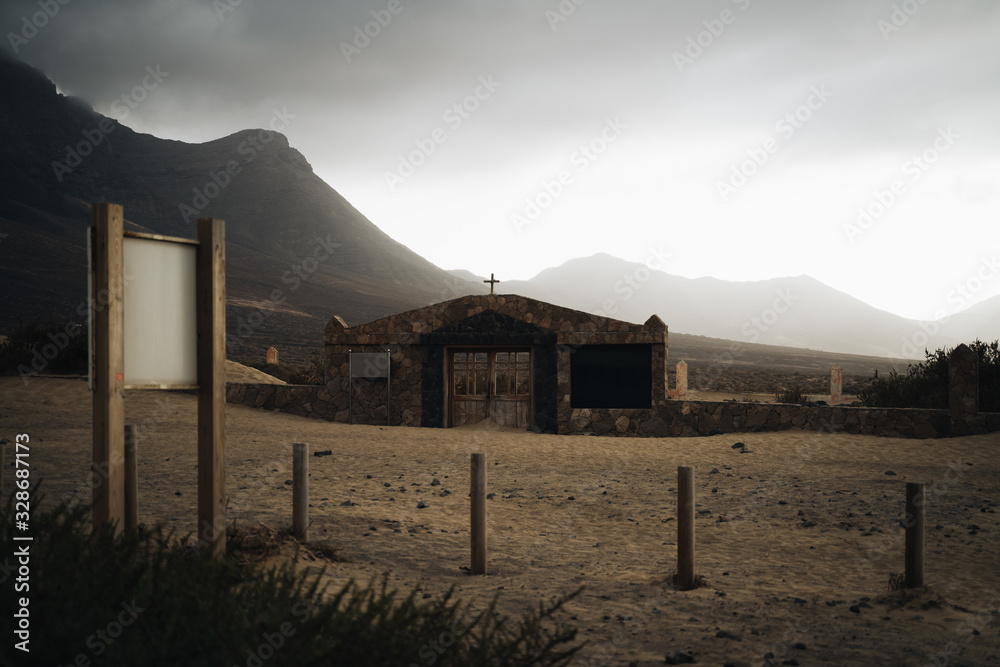 Abandoned church in cofete beach, Fuerteventura, Spain with rocky mountains in the background