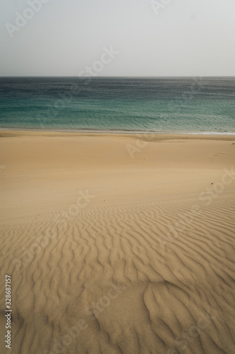 Very calm shot of beach with textured sand hills and blue water
