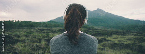 Canvas Print Woman in headphones listening music in nature and at the mountain