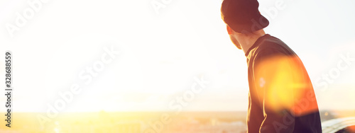 Canvas Print Young and brave man sitting on the edge of the roof and looking far away at the
