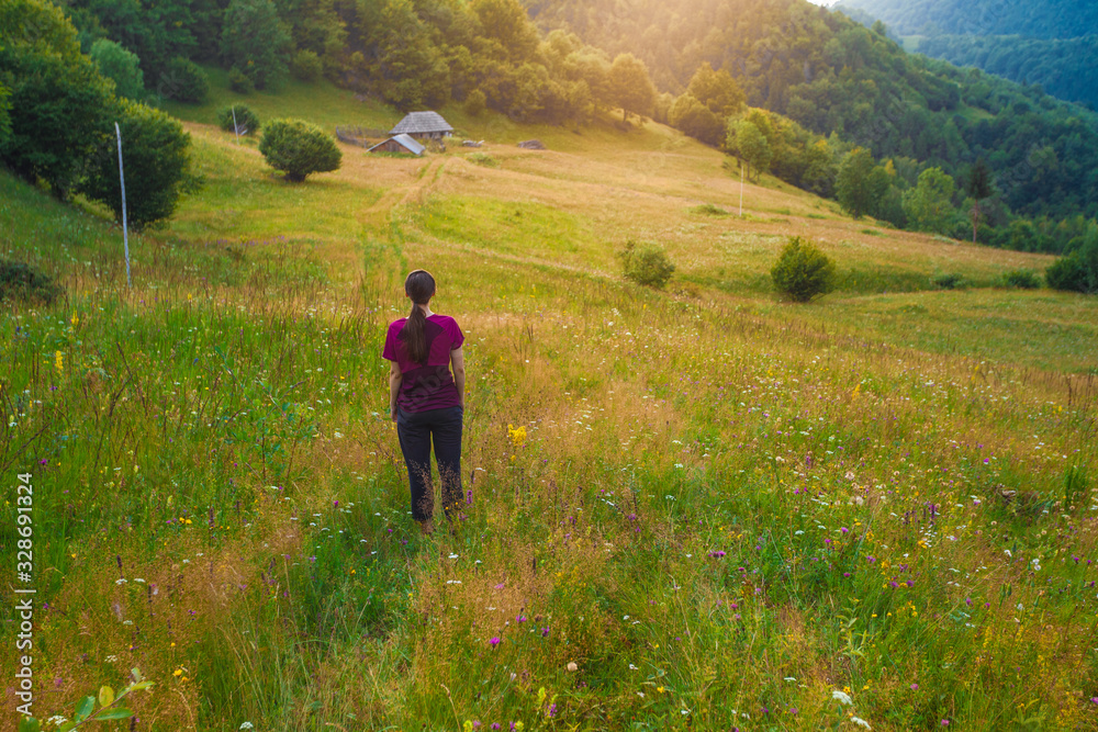 Girl walking through peaceful rural countryside grassland