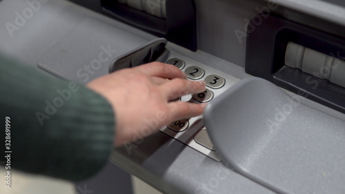 A young woman enters a password at an ATM. ATM for cash withdrawal and deposit. Woman's hand close up