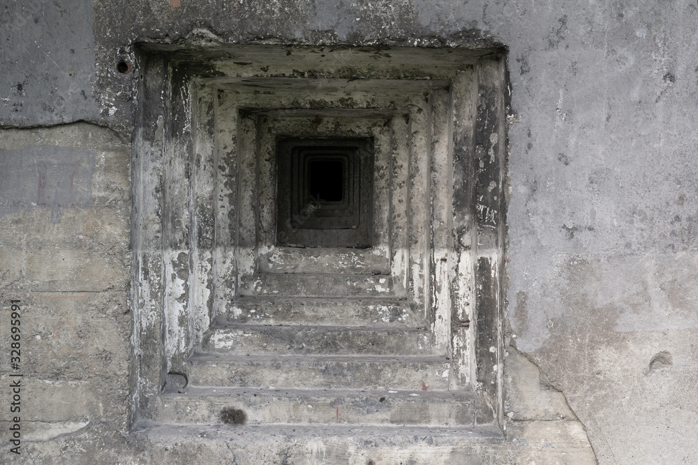 Detail of military bunker and pillbox from world war two - steppen embrasure and hole for gun in the grey wall made of concrete.