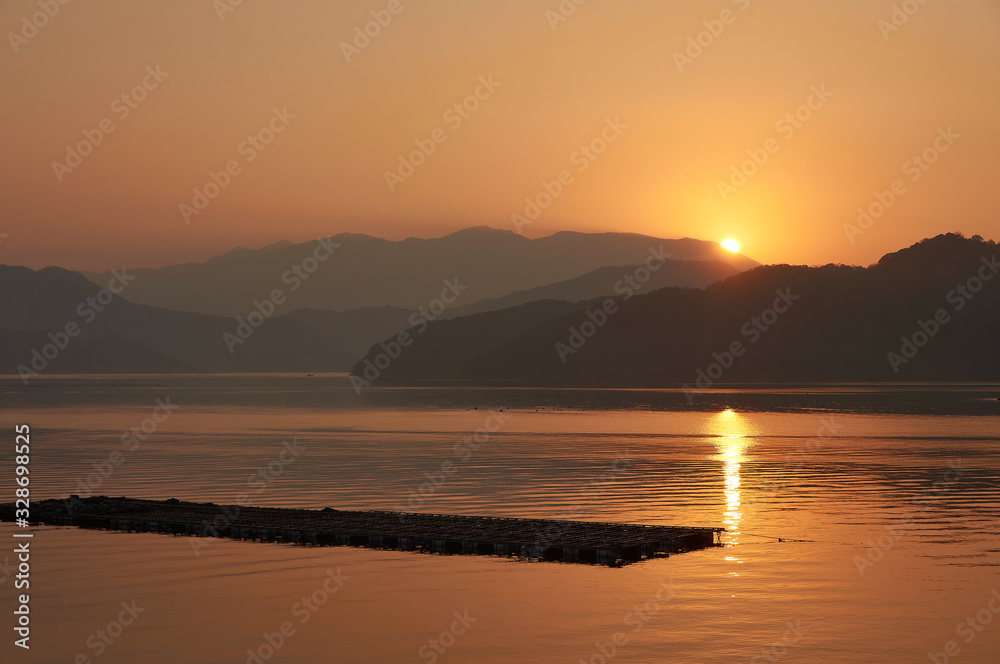 水産養殖筏。 日本の漁村の風景。 鮮やかなオレンジ色の夕日。