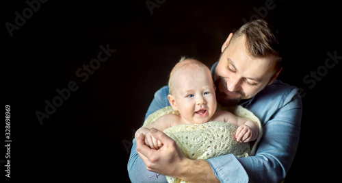 A happy father lives in the arms of a newborn baby, hugs and poses creamly. Paternity