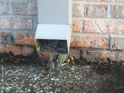 фотографія closeup of rain spout and brick wall with draining water