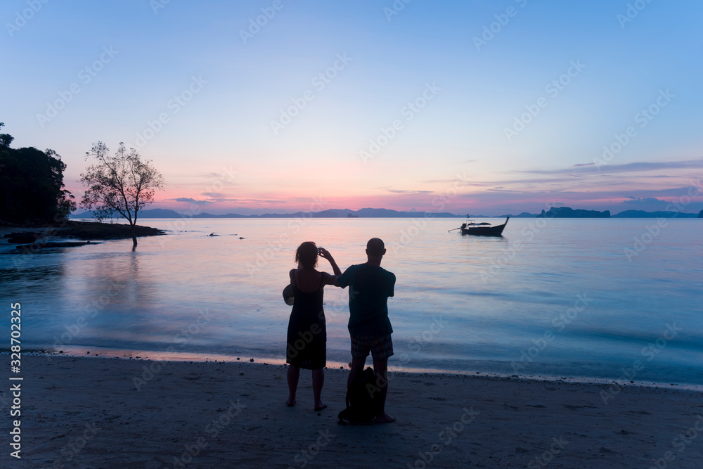 Silhouette of tourist is watching beautiful sunset on the beach in Krabi, Thailand during summer vacation time. Silhouette of tourist is watching beautiful sunset on the beach in Krabi, Thailand during summer vacation time.