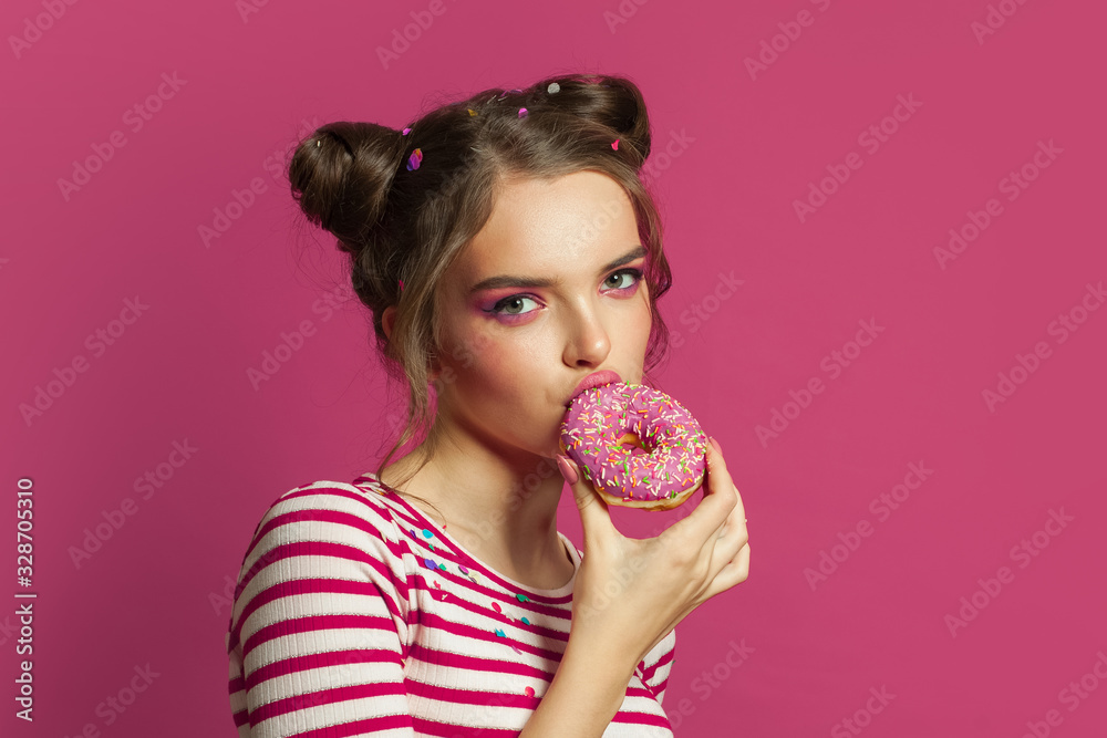 Perfect model woman eating testy donut on colorful pink background