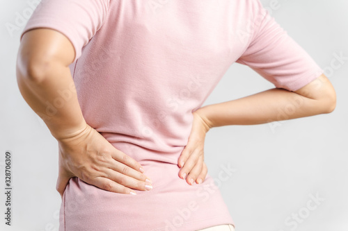 Young woman feeling pain in her back on white background. Healthcare and medical concept.
