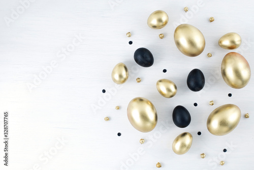 Minimal gold eggs easter concept. Stylish easter golden and black eggs on white wooden background. Flat lay trendy easter. Happy easter card with copy space for text