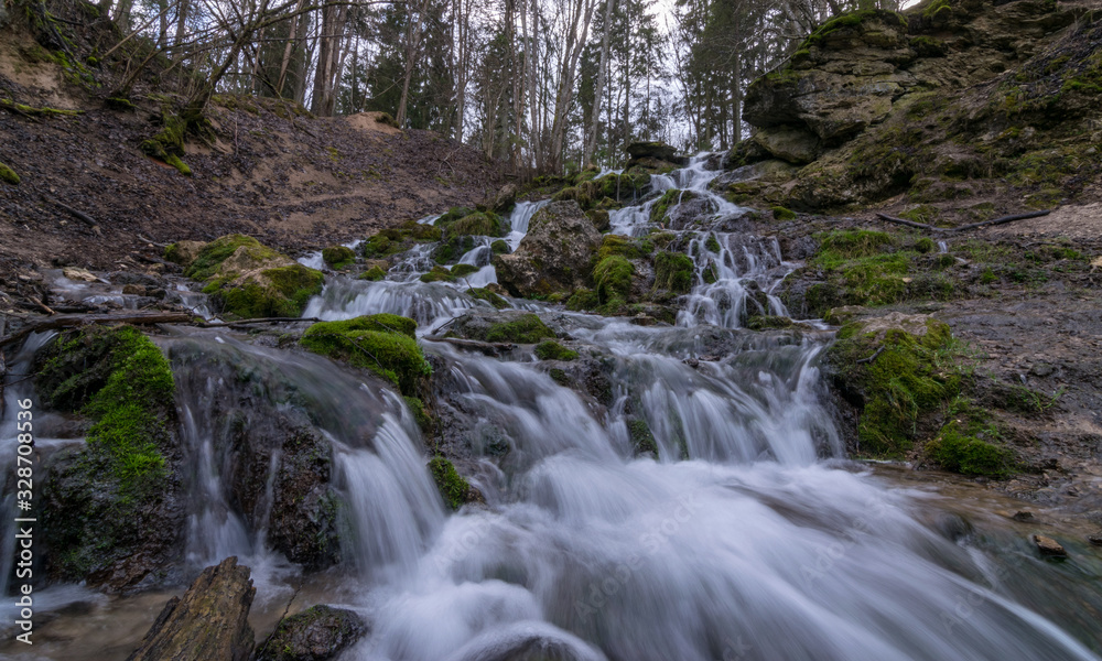 A stream of water flowing over rocks and creating a waterfall effect.