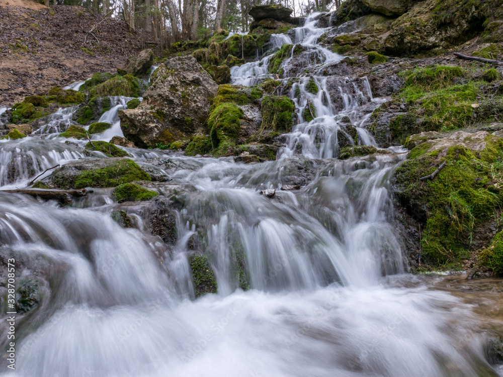 A stream of water flowing over rocks and creating a waterfall effect.