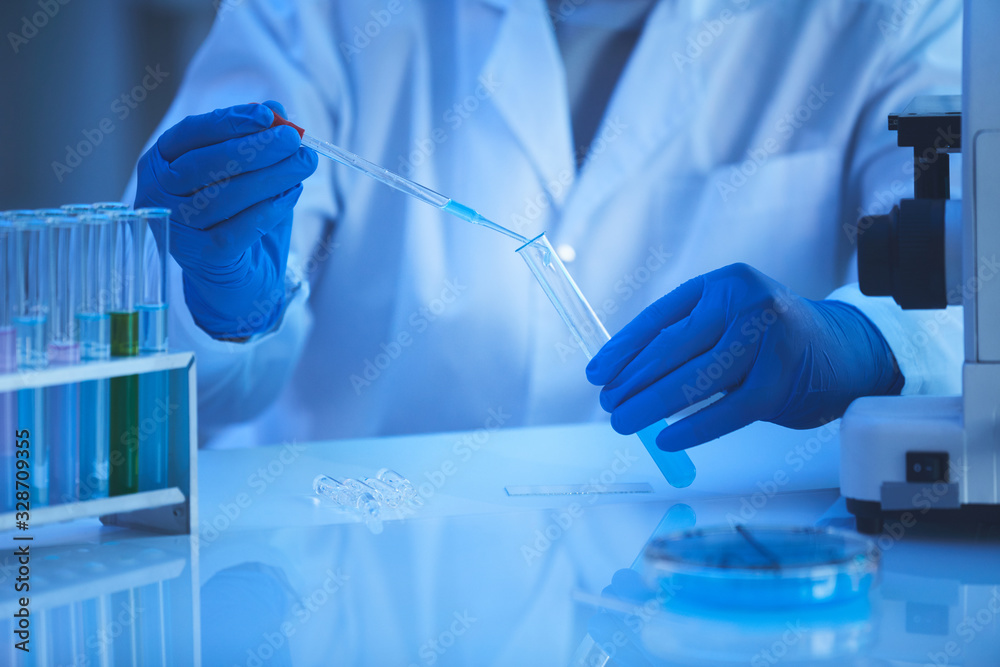 Horizontal close up shot of unreconizable laboratory scientist taking specimen out from test-tube using pipette