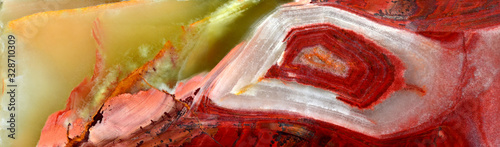Onyx, variety of agate. The texture of the surface of a beautiful stone. Green, brown, red, white, yellow color of the stains on a semi-precious mineral. Panoramic view