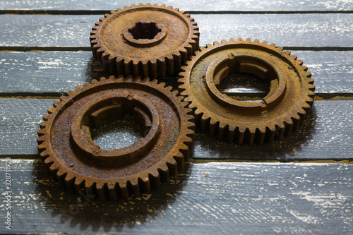 Old rusty gears from machines on a wooden table.
