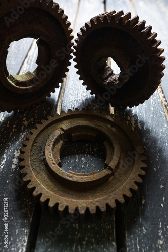 Old rusty gears from machines on a wooden table.