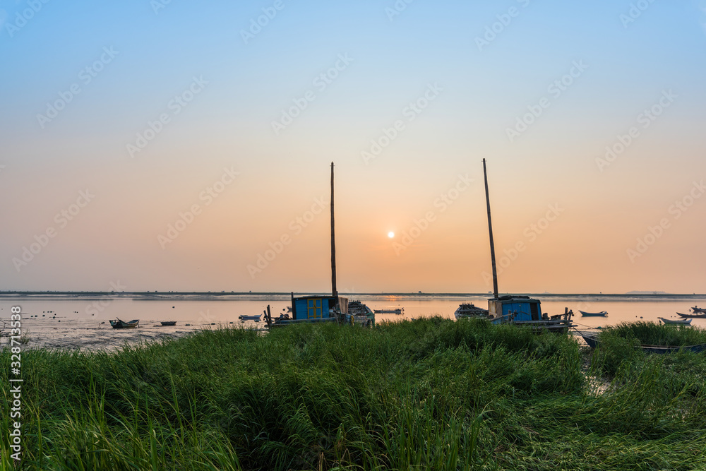 Obraz premium At sunrise on the beach, the masts of the two ships stretched into the sky
