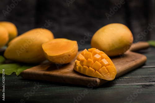 Mango on the wooden table, with cut pieces and complete