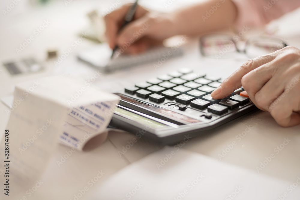 Pension calculation concept, old hands counting finances on a home calculator , close- up Pension calculation concept, old hands counting finances on a home calculator , close- up